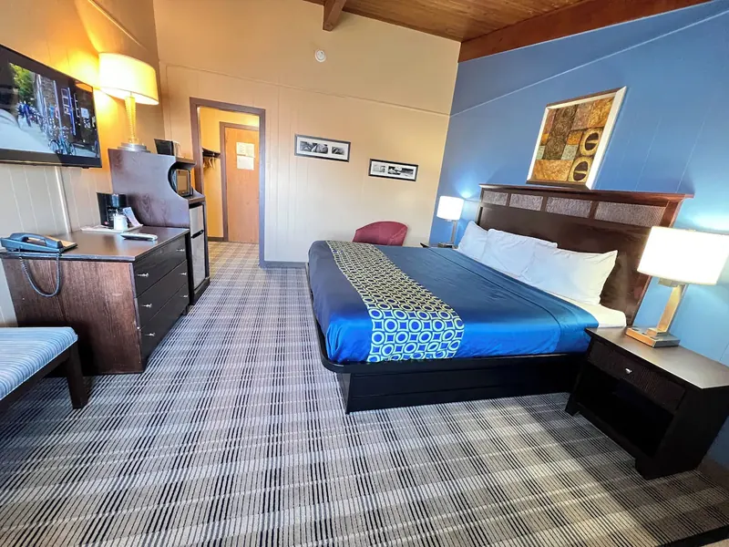 King room with blue bedding, a desk and a wall-mounted television